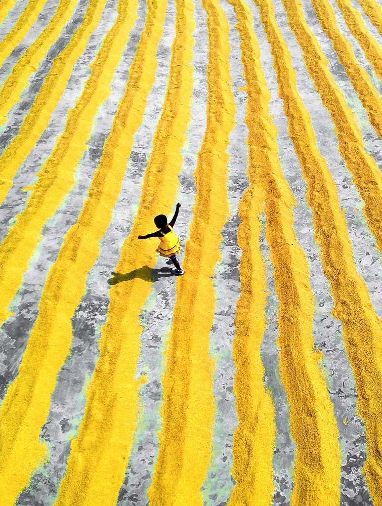 The dancing child in a paddy grain drying yard