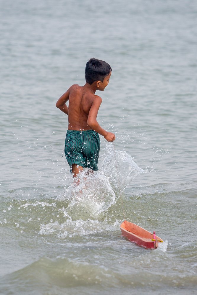 A boy Playing with rubber boat in water.