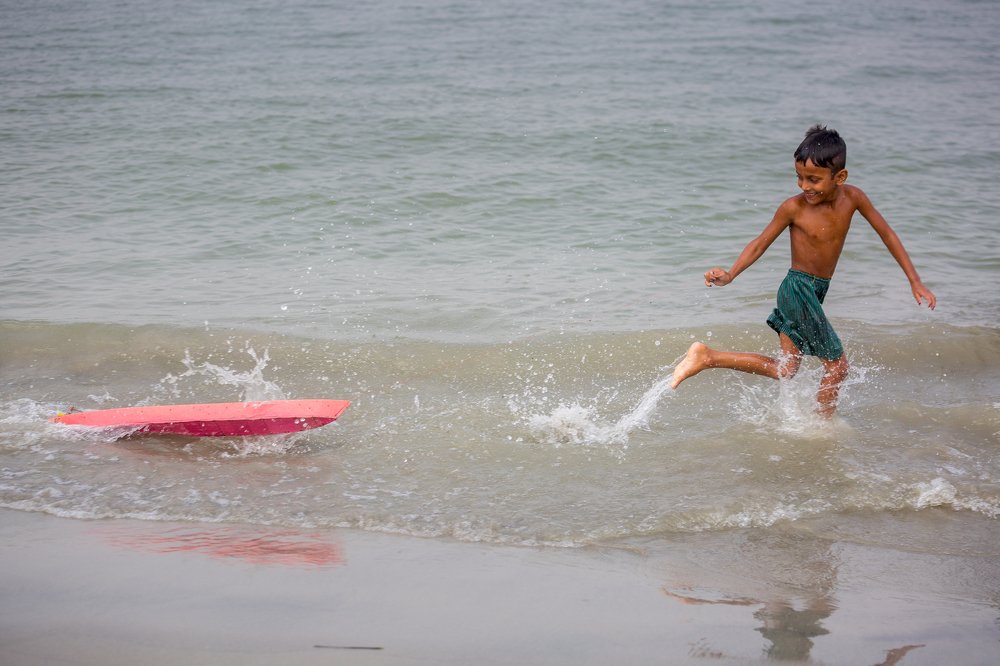 A boy Playing with rubber boat in water.