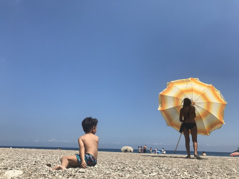 A yellow umbrella is being taken away that was above the boy