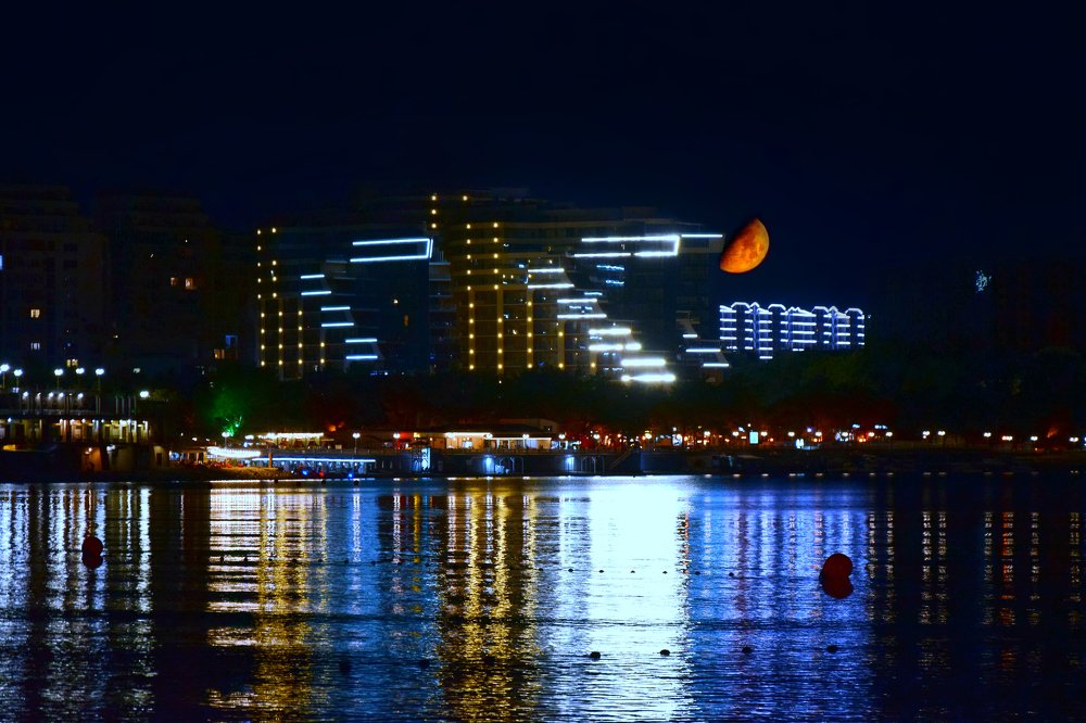 The moon peeps out from behind the houses. (Gelendzhik)
