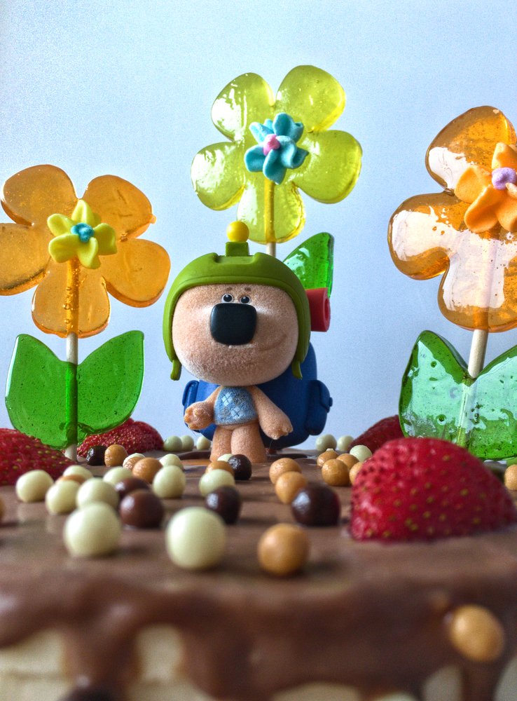 Торт на день рождения, украшенный леденцами, клубникой и медведем Кешей.