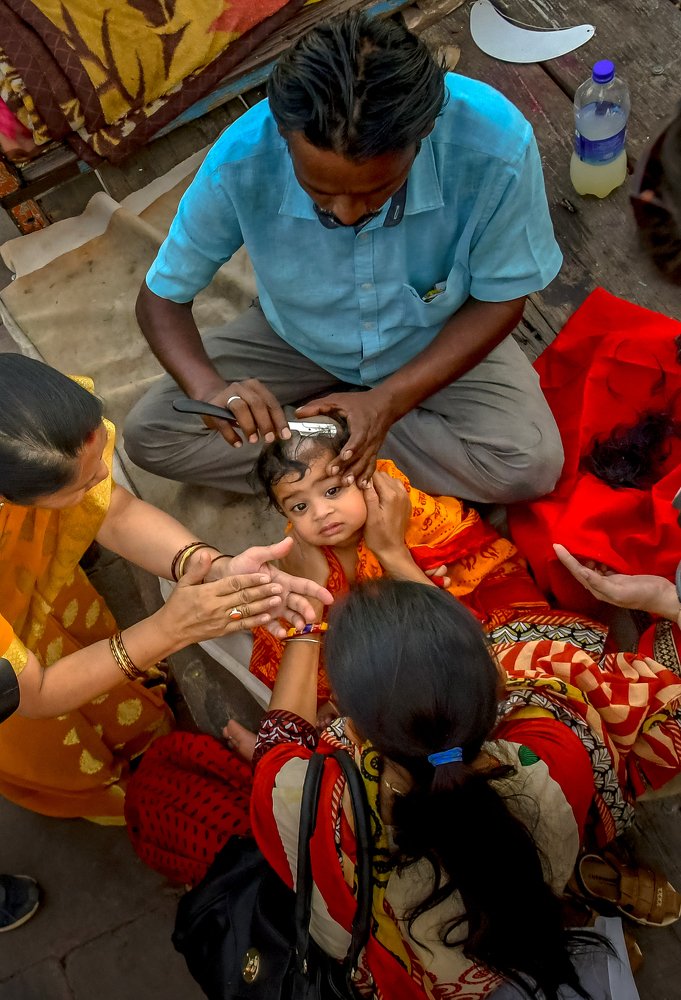 Shaving baby Girl Head ceremony In Indian Holy Color festival