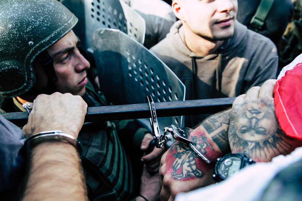 A protester is handcuffed to a fence.