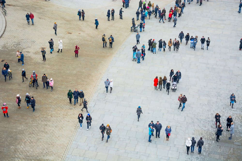 A view from above of the city square with a lot of walking people. Trade pavilions with food and souvenirs