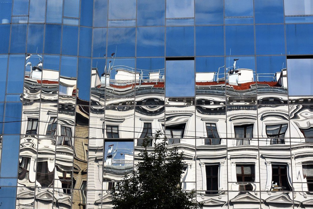 Old city buildings reflection in the glass facade of a modern office house