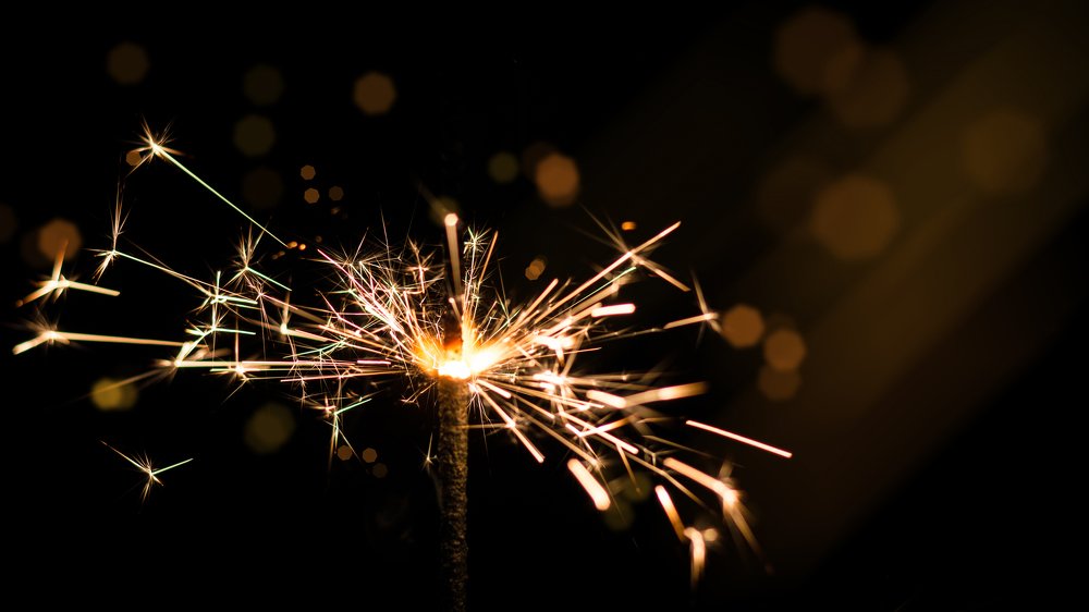 Sparkler in yellow and orange light on a black background