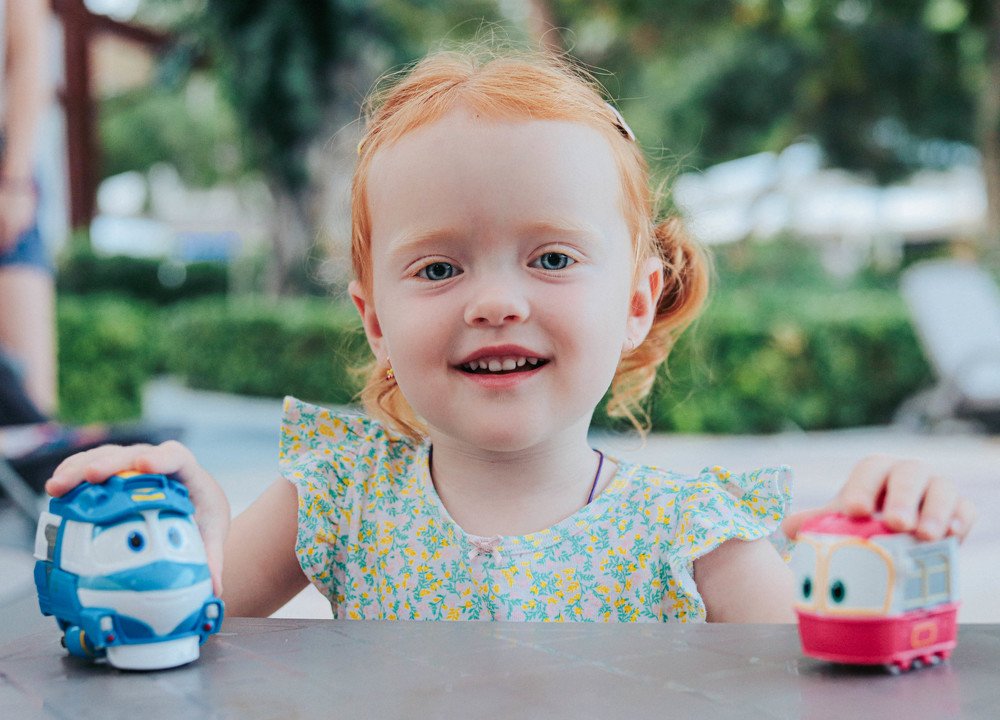 Кукла играет с машинками.