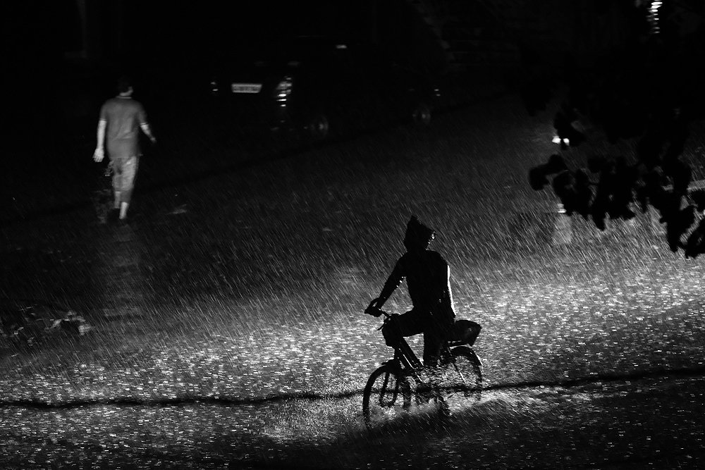Man on cycle on rainy night