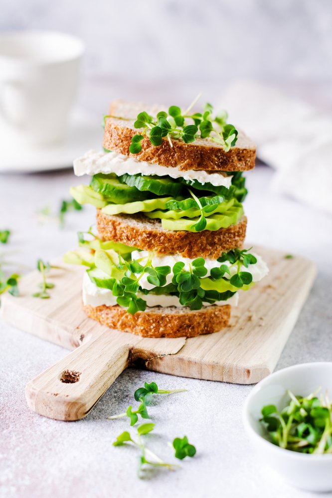 Avocado, cucumber and feta cheese sandwich decorated with micro-greens.