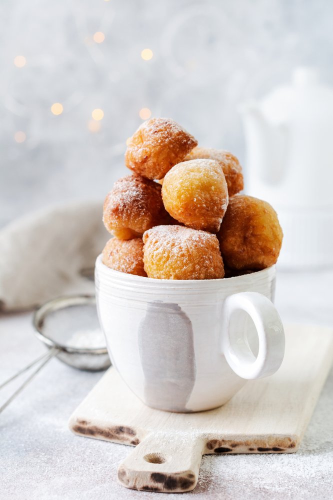 Little Donuts with icing sugar in a vintage ceramic cup.
