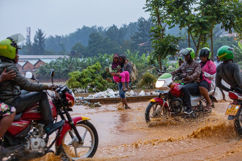 Pedestrians and motorists risk their lives to transport passengers in a flooded road in Kigali on 28 January 2020.