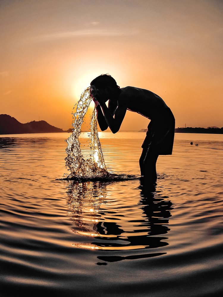 Silhouette of a boy washing his face