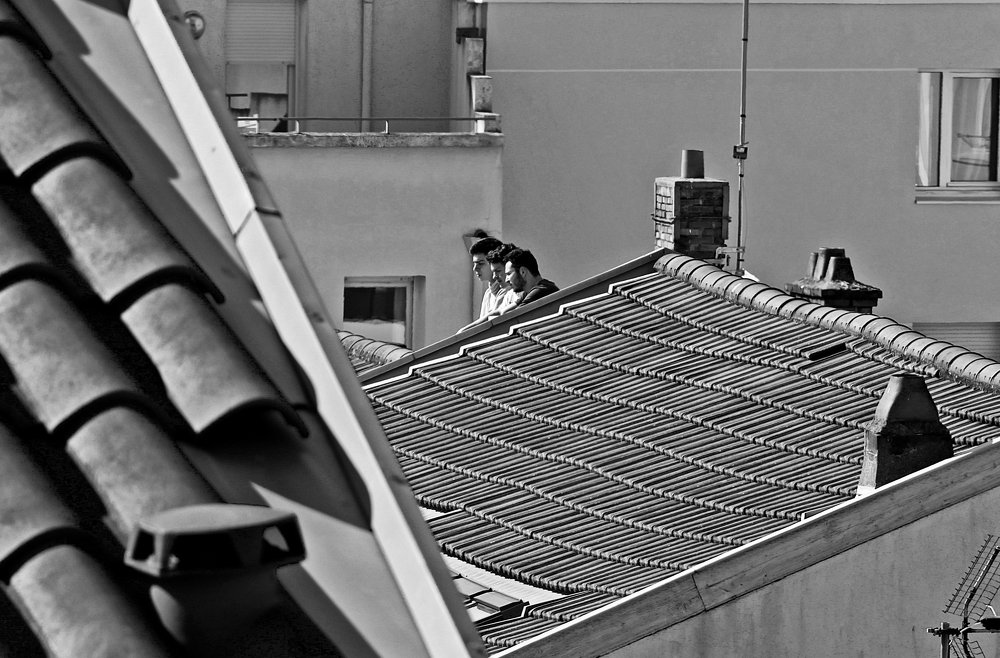 Three guys on the roof look at the deserted city