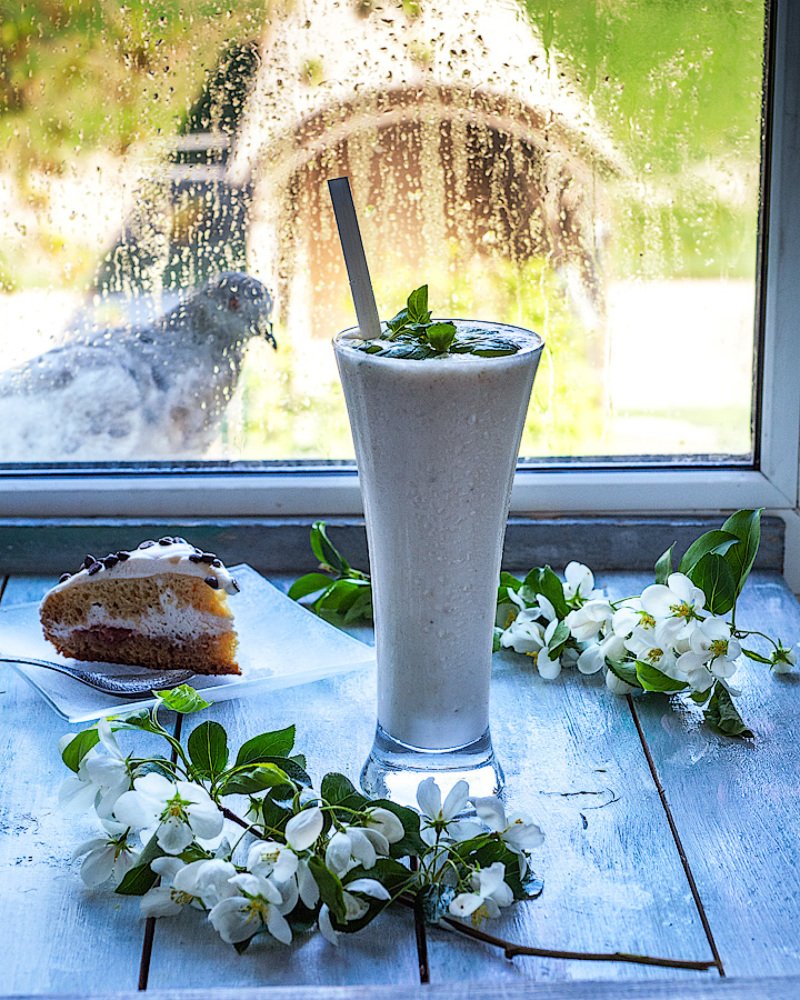 Молочной коктейль в высоком бокале и яблоневый цвет