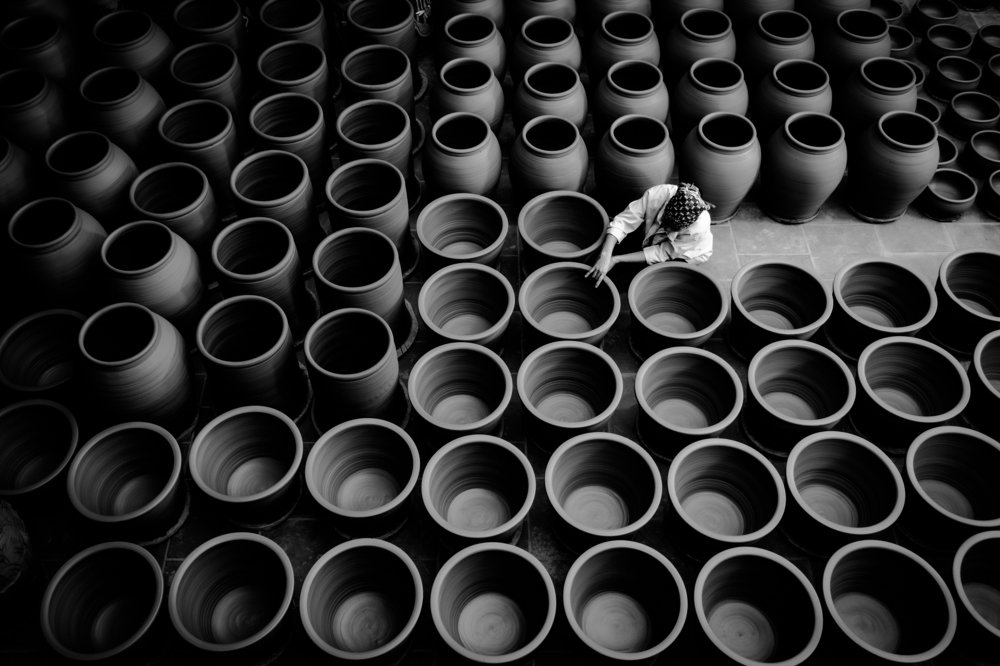The worker produces ceramic pots from clay