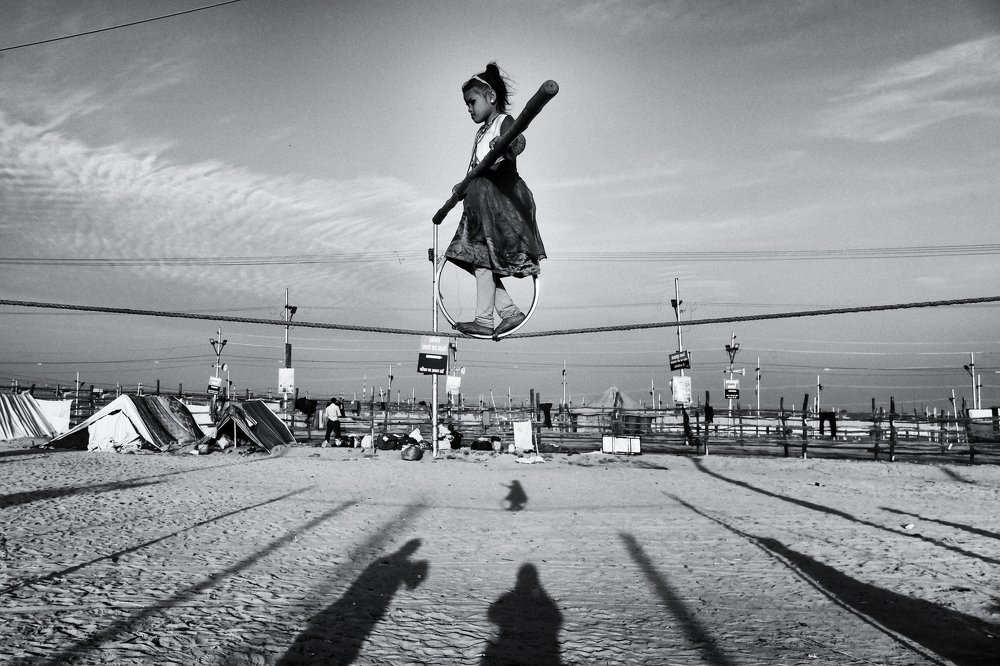A glid walks on a rope as a street performe