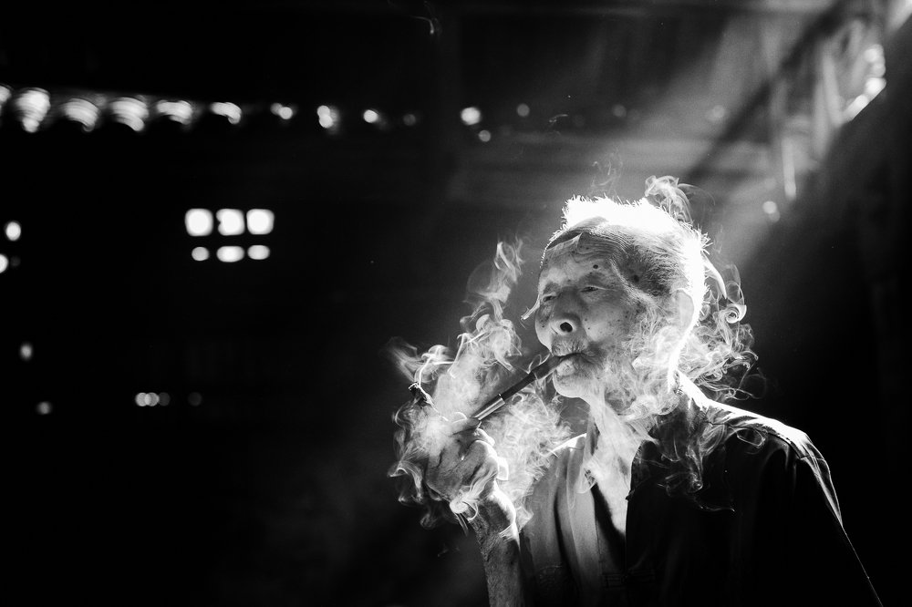 The smoker. Chinese man smoking traditional pipe