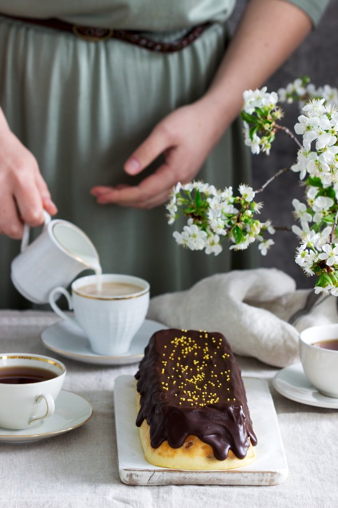 Cheesecake and a woman pouring milk into tea. Чизкейк и женщина, наливающая молоко в чай.