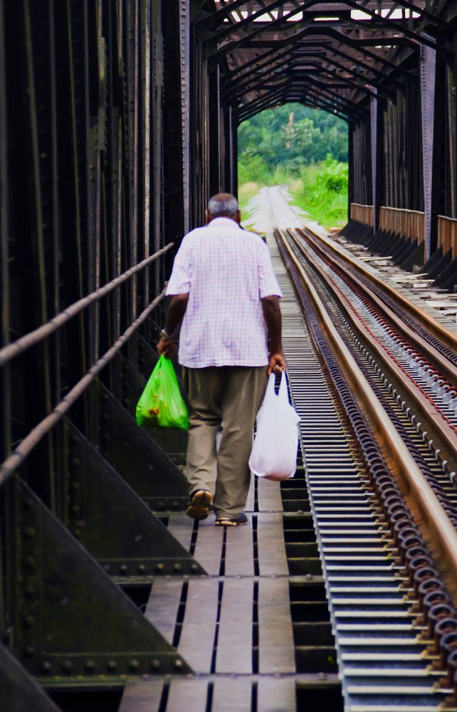 An Old man is crossing the railway bridge.