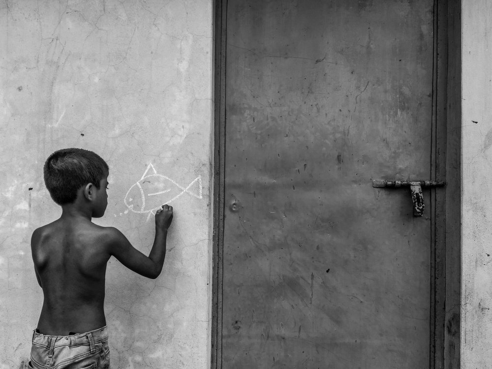 The child is painting on the wall