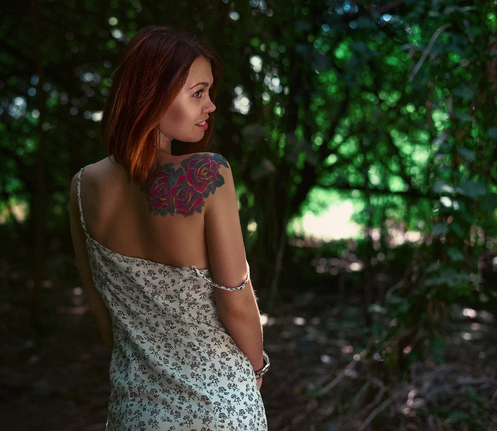 A young girl with a rose on her shoulder.